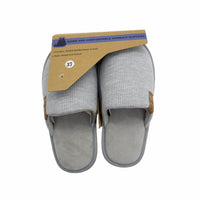 Women's slip-on slippers in light gray knit with tan trim, hanging from a retail tag