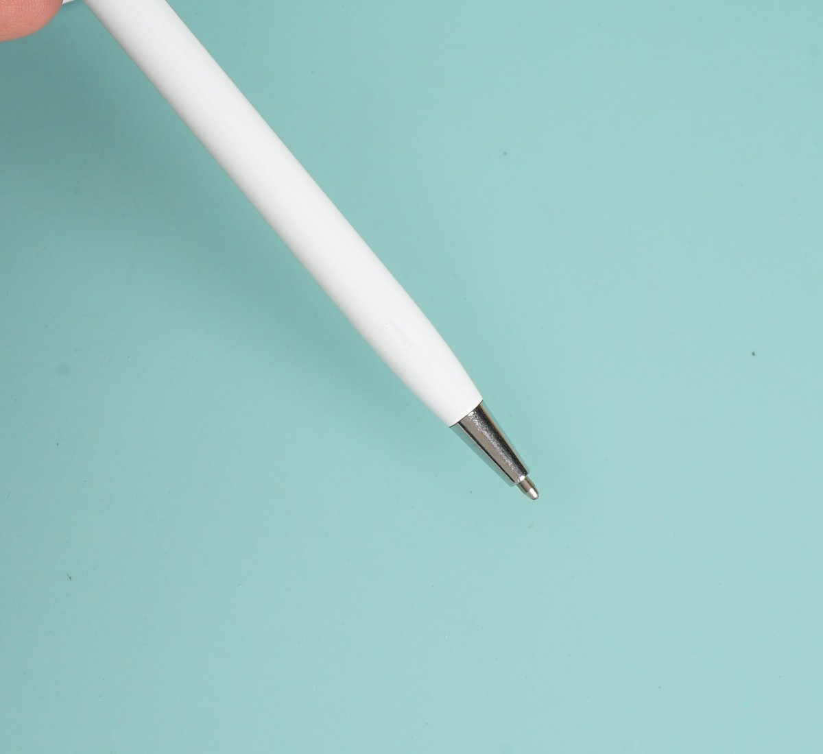 White ballpoint pen with metal tip, angled view