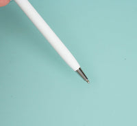 White ballpoint pen with metal tip, angled view