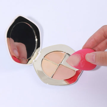 Makeup sponge puffs in a compact case, one sponge held between fingers