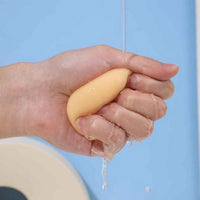 Teardrop makeup sponge held under running water, yellow with droplets