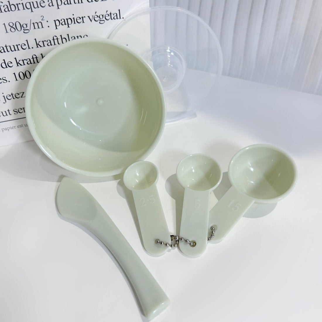Beauty measuring kit with four light green measuring cups and metal chain
