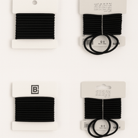 Elastic band set of black hair ties on retail cards, showing coiled bands and loops.