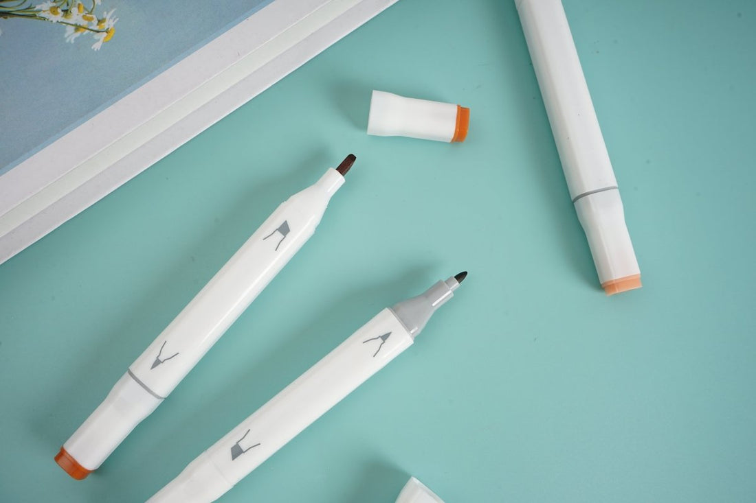 Three highlighter pens, white barrels with orange tips and printed nib shapes