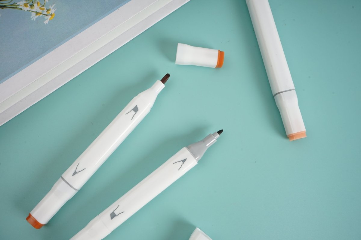 Three highlighter pens, white barrels with orange tips and printed nib shapes