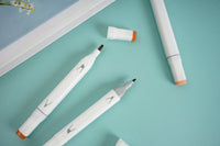 Three highlighter pens, white barrels with orange tips and printed nib shapes