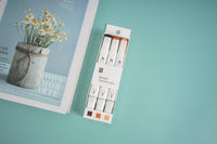 Pack of three brown highlighter pens in retail box, white barrels and orange tips