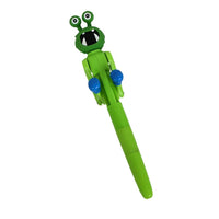 Green cartoon frog ballpoint pen, angled view with blue grips and frog head