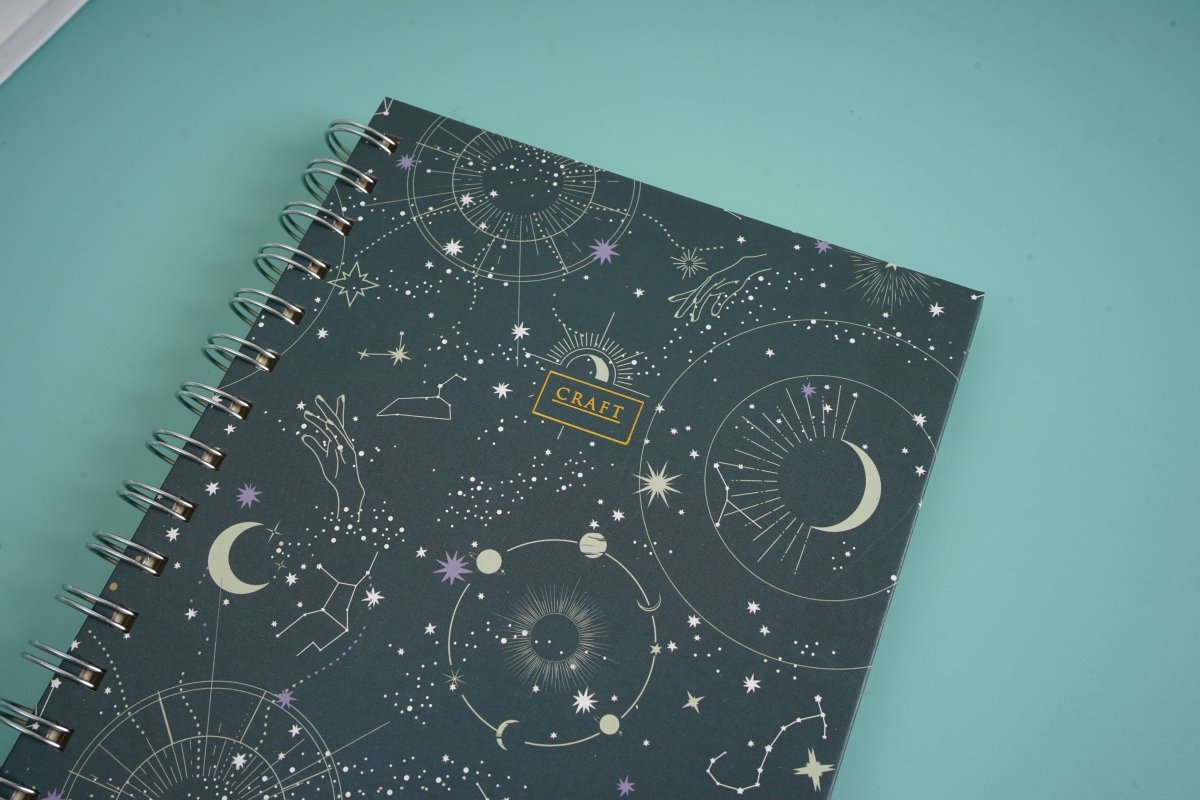 Celestial notebook cover close-up with moons, stars, and a small CRAFT label.