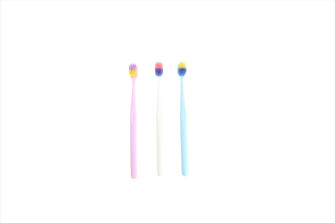 3 toothbrushes with pink, white, and light blue handles and multicolor bristles