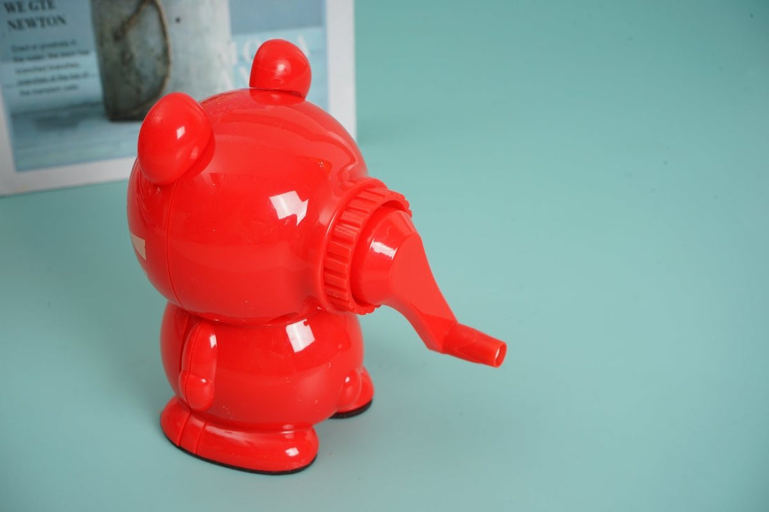 Red bear-shaped hand pencil sharpener, side view with crank and pencil slot
