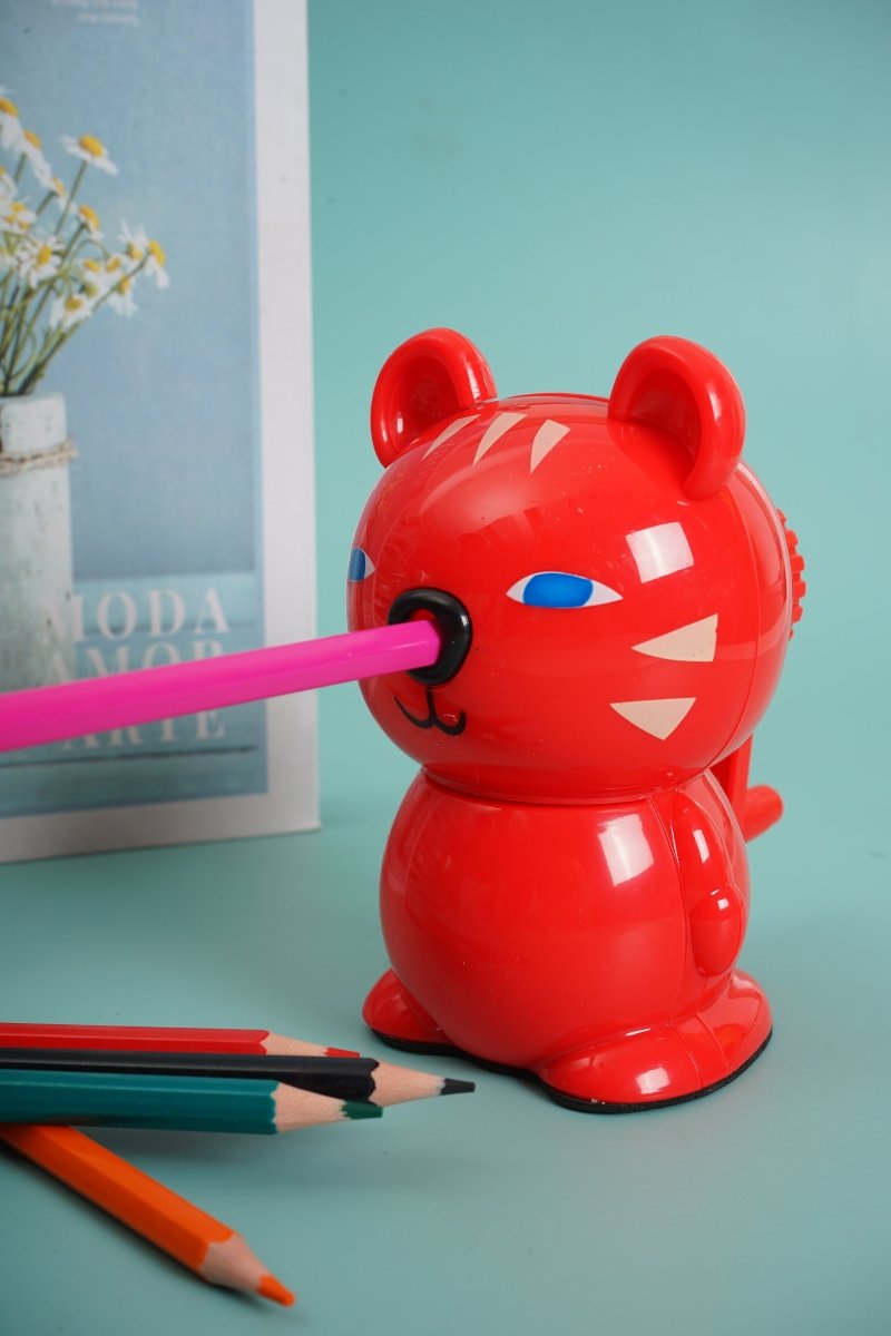 Red bear-shaped hand pencil sharpener with blue eyes and pencil in sharpener slot