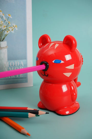 Red bear-shaped hand pencil sharpener with blue eyes and pencil in sharpener slot