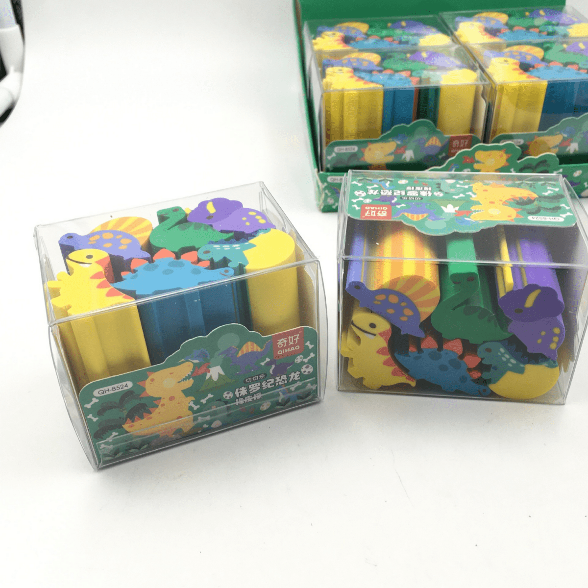 Dinosaur erasers in clear boxes, showing assorted yellow, blue, green, and purple dinosaurs