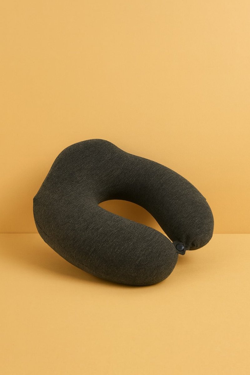 Neck travel pillow in dark gray fabric with button fastener at one side.