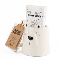 Cream ceramic bear-face mug with Warm Vibes booklet and brown Bear Mug Kit tag
