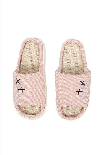 Pink fabric house slippers with beige interior and stitched bear-face motifs