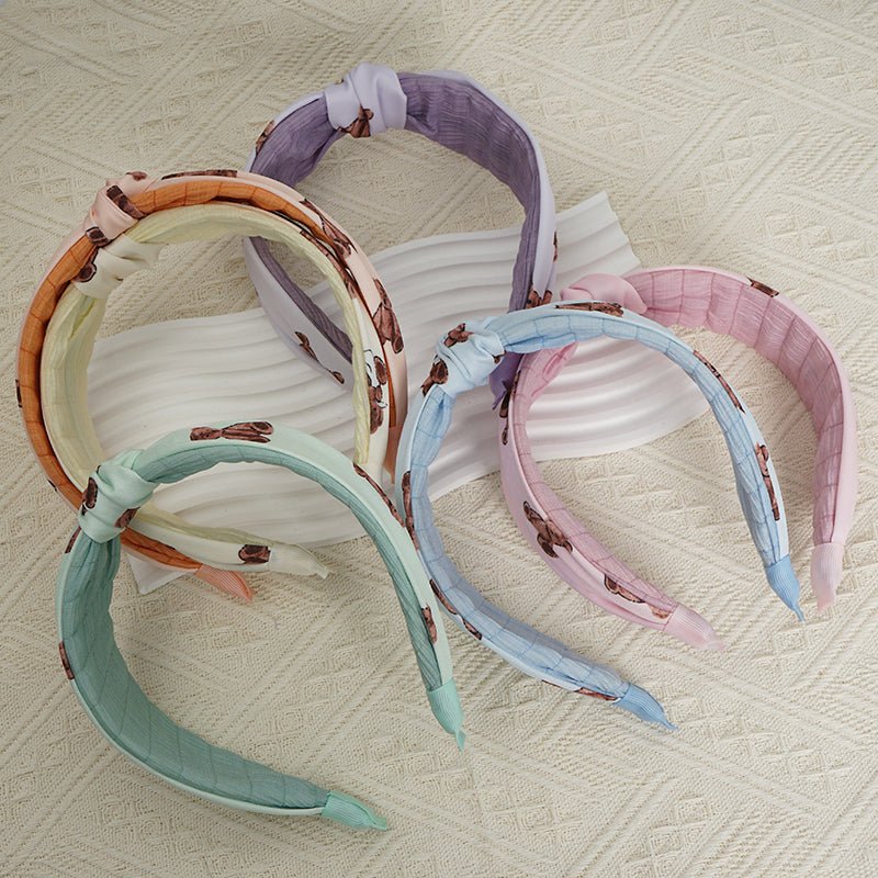Assorted knotted printed hairbands in pastel colors, laid flat with brown motifs