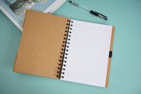 Open spiral notebook with lined pages and black pen clipped at the side