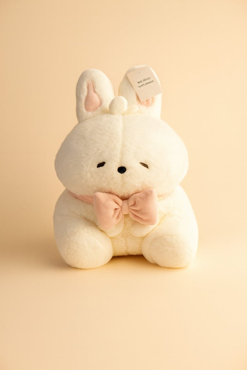 White bunny plush toy with pink bow, seated, soft fabric, front tag