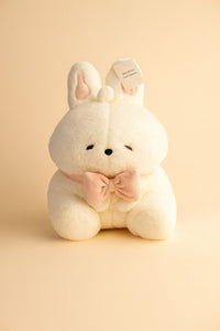 White bunny plush toy with pink bow, seated, soft fabric, front tag