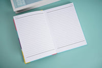 A5 hardback notebook open, two-page spread of lined paper.