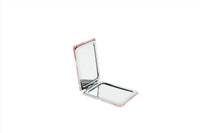 Compact mirror open with orange-edged frame and glass visible