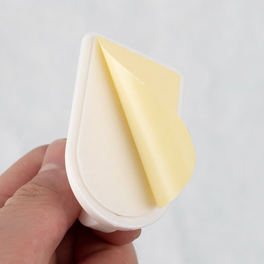 Wall hook adhesive backing, white curved base with beige foam pad