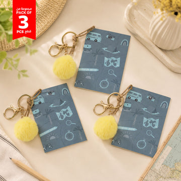 Pack of 3 blue mini notebooks with yellow pom pom keychains, patterned covers