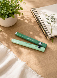 Two panda pens from a 4-pack, green and mint, lying beside an open notebook