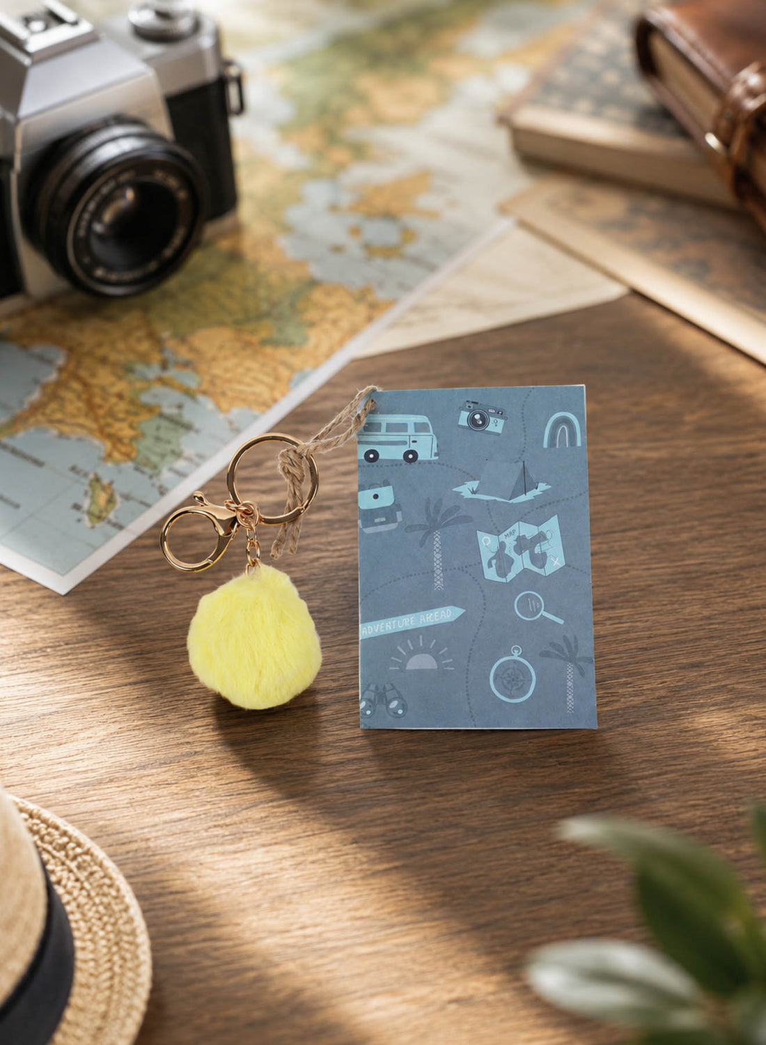 Blue mini notebook with yellow pom pom keychain and travel icon cover