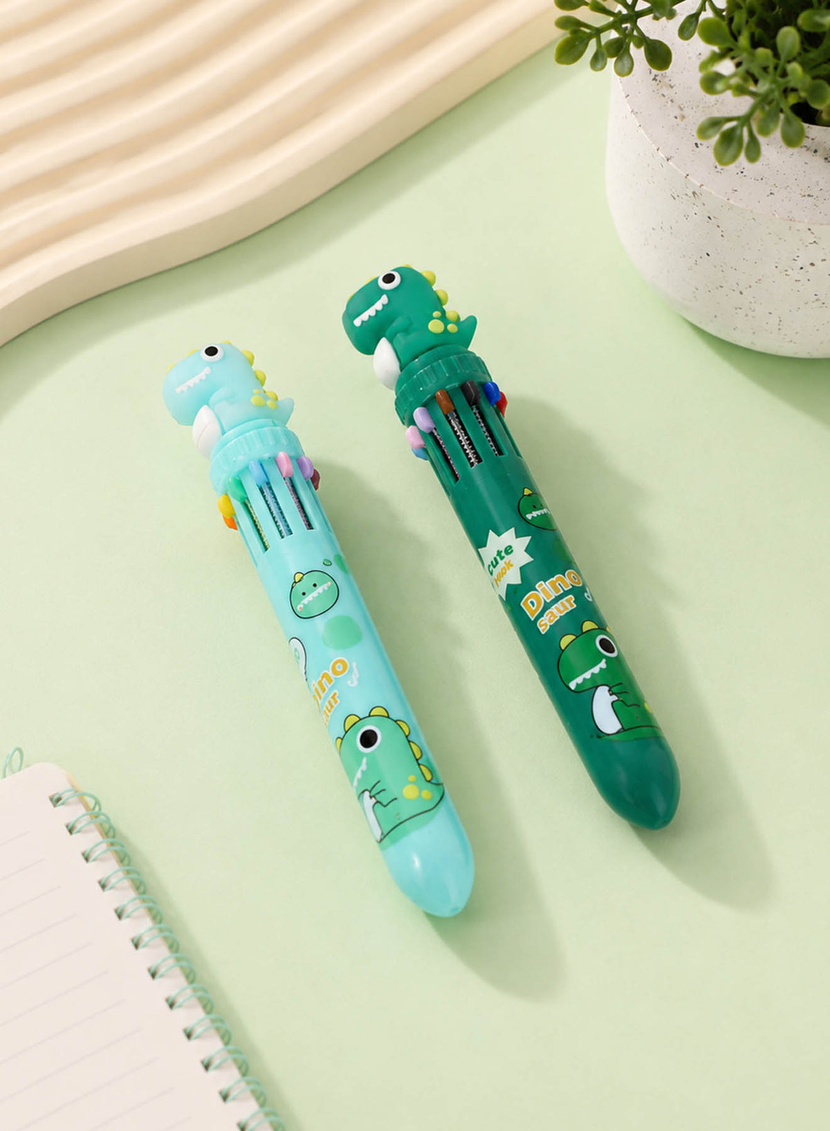 Set of four dinosaur cartoon pens, two light blue and two dark green, dinosaur head caps