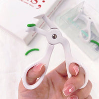Eyelash curler used on lashes, white frame with green handle in hand.