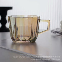Amber glass mug with wide handle, faceted sides and clear base.