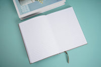 Cloth bound hardback notebook opened, blank white lined pages with stitched spine
