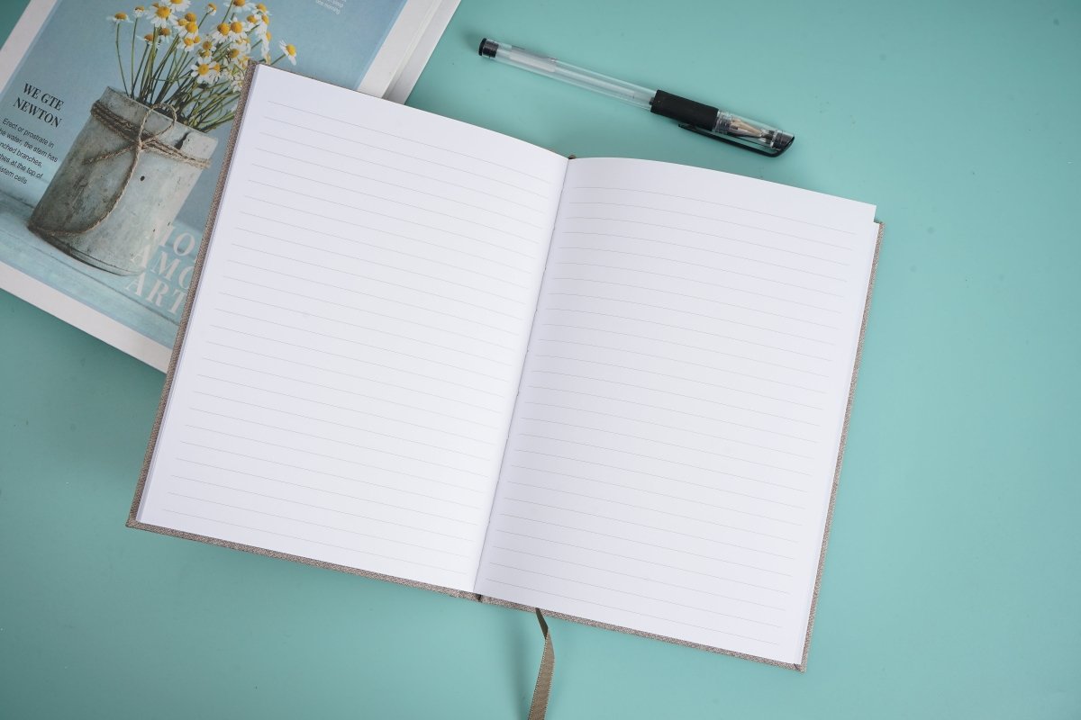 Cloth bound hardback notebook open flat, two white lined pages and cloth spine tie