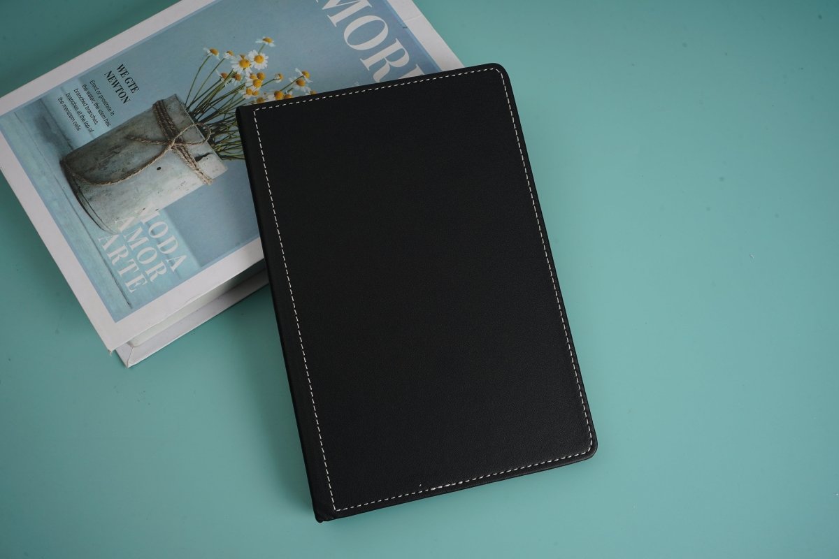 Black notebook with stitched cover, closed and angled