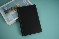 Black notebook with stitched cover, closed and angled