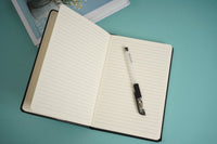 Open black notebook with lined pages and pen inside