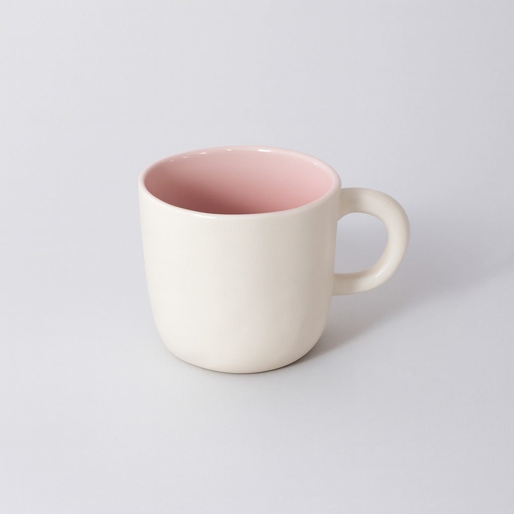 Ceramic cup with cream exterior and pink interior, rounded handle and smooth lip