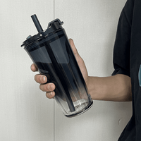 Reusable coffee cup with straw, held at angle in dark clear plastic