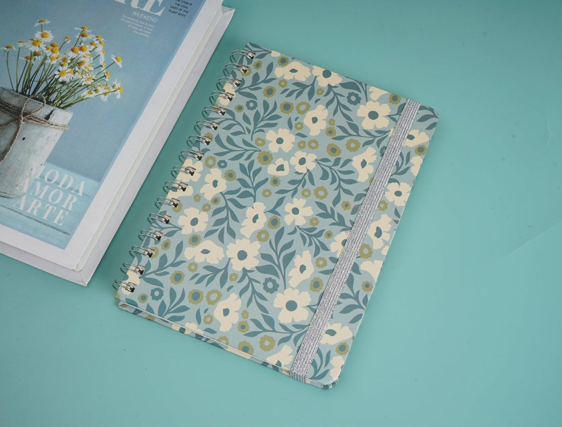 Floral notebook with cream cover, blue and yellow flowers, spiral rings, patterned spine trim