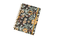 Hardcover spiral notebook with dark floral cover and gold ring binding, front view.