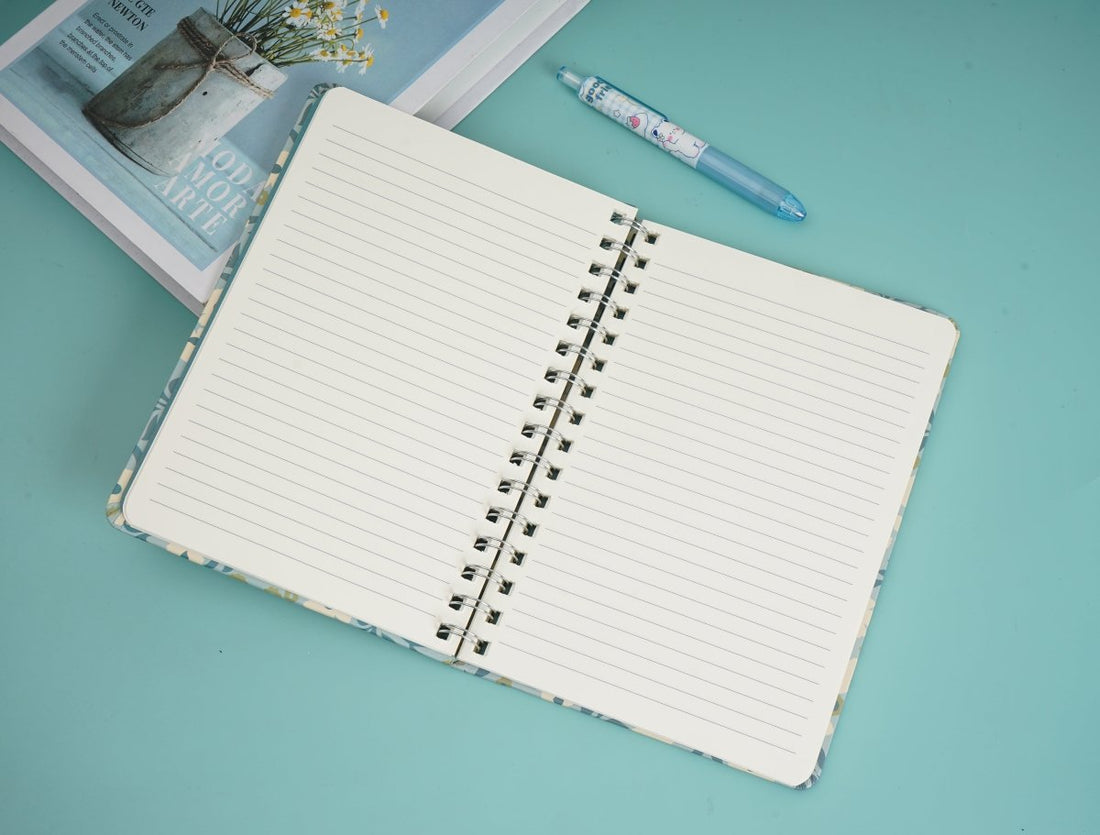 Floral notebook open with ruled pages, dark spiral binding, cream patterned cover