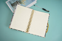 Open hardcover spiral notebook with lined pages and gold rings, flat lay view.