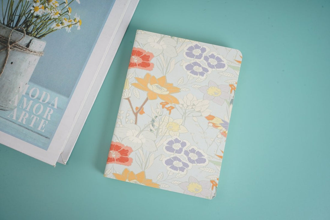 A6 notebook with white floral cover and orange blossoms, closed