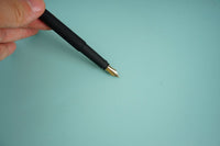 Black fountain pen with gold nib held by a hand
