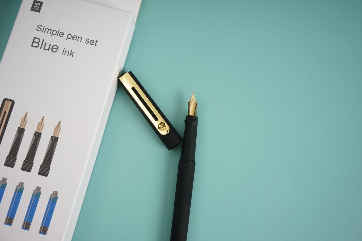 Black fountain pen with gold nib and cap, beside boxed set