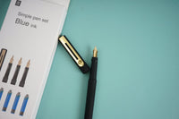 Black fountain pen with gold nib and cap, beside boxed set