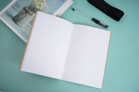 Open kraft notebook with white pages and black elastic strap visible